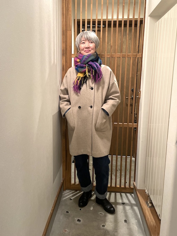 ベージュのコートにチェック柄のストールを巻いた女性
